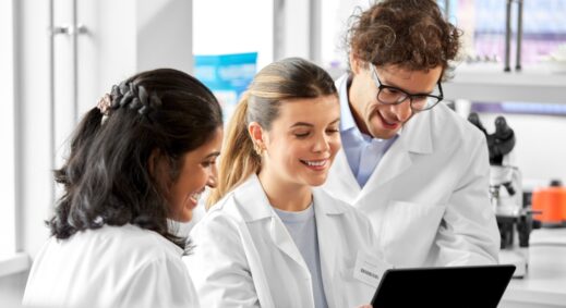 Three scientists reviewing documents in laboratory.